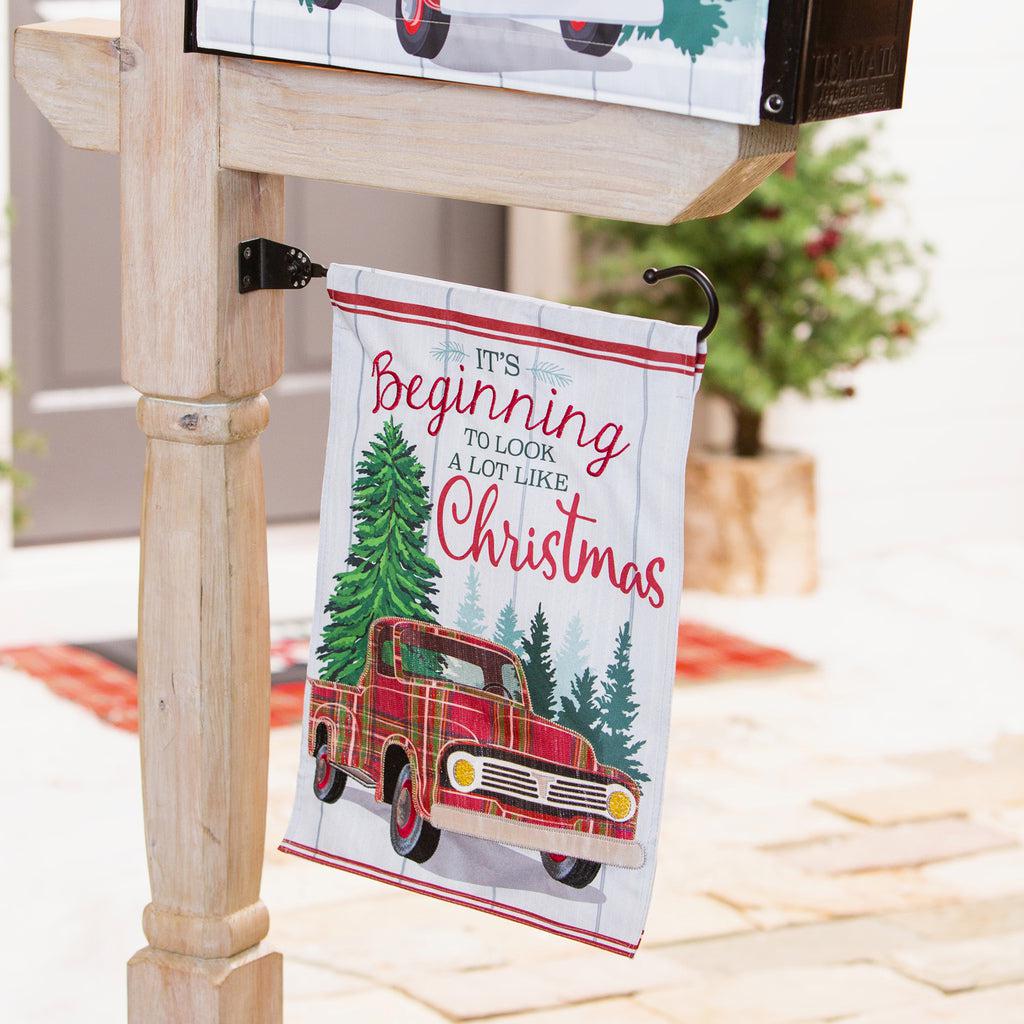 The Plaid Christmas Truck garden flag features a vintage plaid truck, pine trees, and the words "It's Beginning to Look a Lot Like Christmas". 